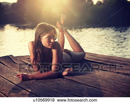Young woman in bikini lying on jetty, looking away View Large Photo Image Stock Photo - Young woman in bikini lying on jetty, looking away. Fotosearch