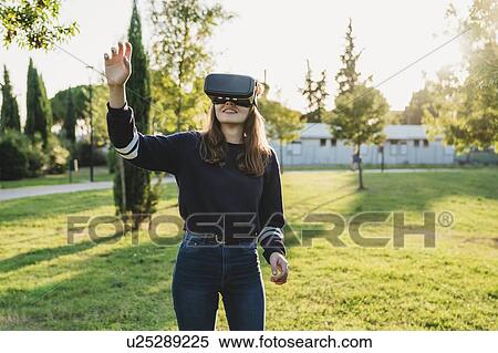 Young woman looking through VR headset in park View Large Photo Image Stock Photography - Young woman looking through VR headset in park. Fotosearch