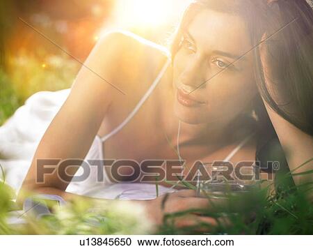 Young woman lying in meadow, leaning on elbow View Large Photo Image Stock Image - Young woman lying in meadow, leaning on elbow. Fotosearch
