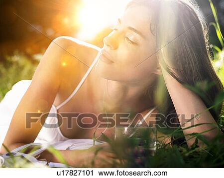 Young woman lying in meadow, leaning on elbow View Large Photo Image Stock Image - Young woman lying in meadow, leaning on elbow. Fotosearch
