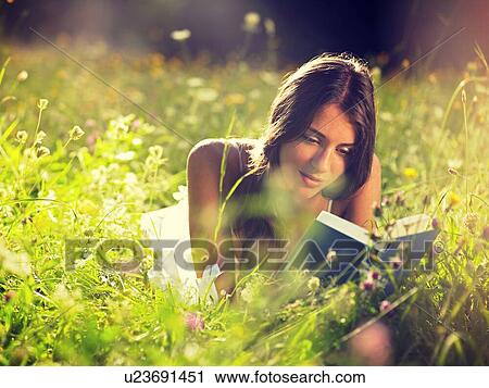 Young woman lying in meadow reading book View Large Photo Image Stock Image - Young woman lying in meadow reading book. Fotosearch
