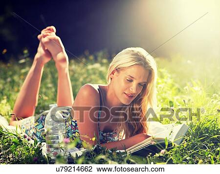 Young woman lying in meadow reading book View Large Photo Image Stock Image - Young woman lying in meadow reading book. Fotosearch