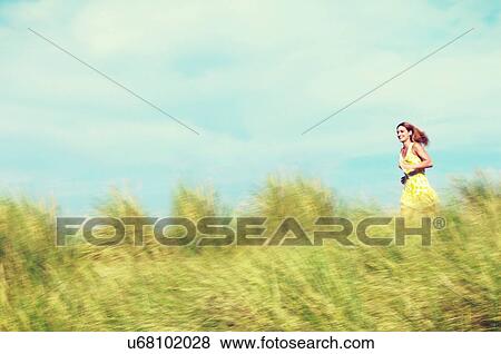 Young Woman Running through Tall Grass View Large Photo Image Stock Photo - Young Woman Running through Tall Grass. Fotosearch
