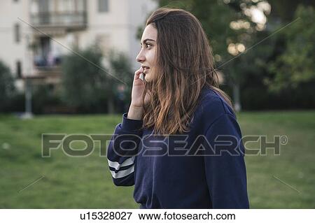 Stock Photo - Young woman using smartphone in park. Fotosearch