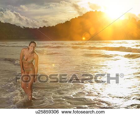 Young Woman Wading in Ocean at Sunset View Large Photo Image Stock Photograph - Young Woman Wading in Ocean at Sunset. Fotosearch
