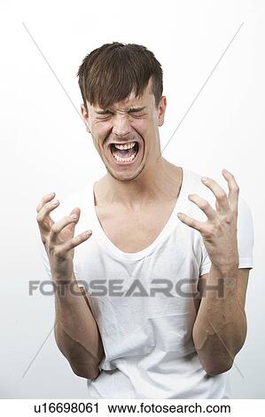 Stock Image - Aggressive young man screaming against white background. Fotosearch