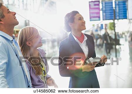 Attractive airport staff holding boarding pass while looking at the monitor in airport View Large Photo Image Stock Image - Attractive airport staff holding boarding pass while looking at the monitor in airport. Fotosearch