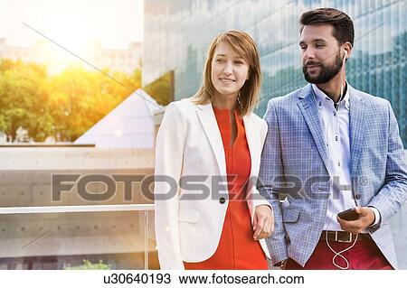 Attractive businessman and businesswoman standing outside office building View Large Photo Image Stock Image - Attractive businessman and businesswoman standing outside office building. Fotosearch