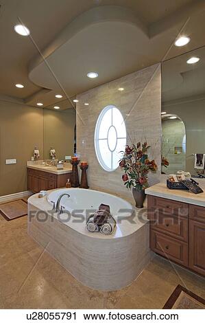 Stock Image - Bath and sink with circular window in luxurious bathroom. Fotosearch