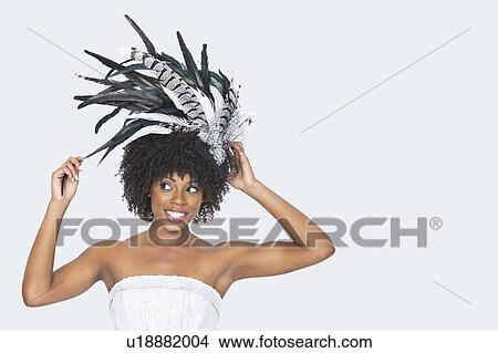 Picture - Beautiful African American bride wearing feather fascinator over gray background. Fotosearch