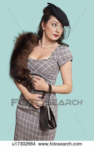 Beautiful young woman in dress carrying fur boa on her shoulder against blue background View Large Photo Image Picture - Beautiful young woman in dress carrying fur boa on her shoulder against blue background. Fotosearch