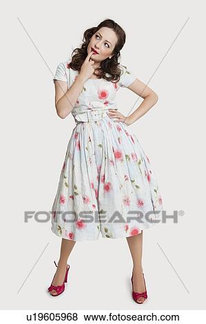Beautiful young woman in dress day dreaming with hand on chin against white background View Large Photo Image Stock Photo - Beautiful young woman in dress day dreaming with hand on chin against white background. Fotosearch