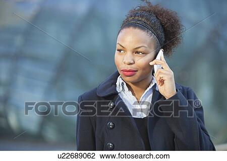 Stock Image - Beautiful young woman in formals using mobile phone. Fotosearch