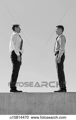 Stock Image - Black and white photo of Businessman standing in office rooftop. Fotosearch