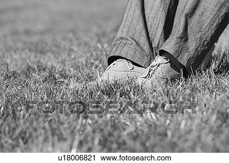 Stock Image - Black and white photo of businessman foot on the grass . Fotosearch