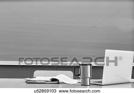 Black and white photo of laptop on professor desk with tumbler and book against black board in classroom View Large Photo Image Stock Image - Black and white photo of laptop on professor desk with tumbler and book against black board in classroom. Fotosearch