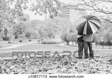 Black and white photo of man holding umbrella while enjoying the lovely view with his wife in park View Large Photo Image Stock Image - Black and white photo of man holding umbrella while enjoying the lovely view with his wife in park. Fotosearch
