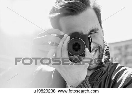 Stock Photo - Black and white photo of Young attractive man photographing the beautiful views in the city. Fotosearch