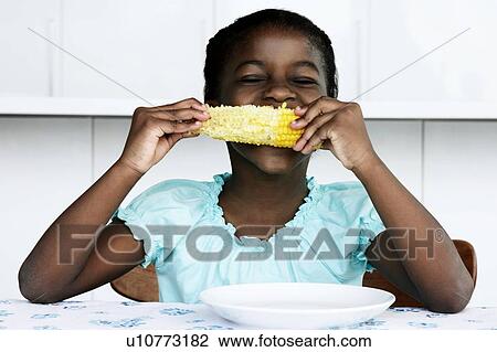Stock Image - Black young girl eating corn cobb. Fotosearch