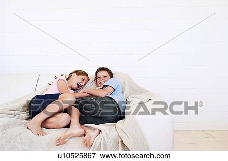 Stock Photo - Brother and sister relaxing on sofa together. Fotosearch