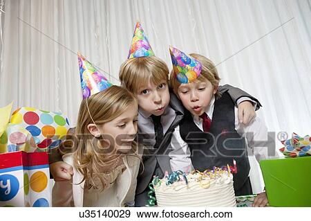 Brothers and sister blowing candles on birthday cake together View Large Photo Image Stock Photo - Brothers and sister blowing candles on birthday cake together. Fotosearch