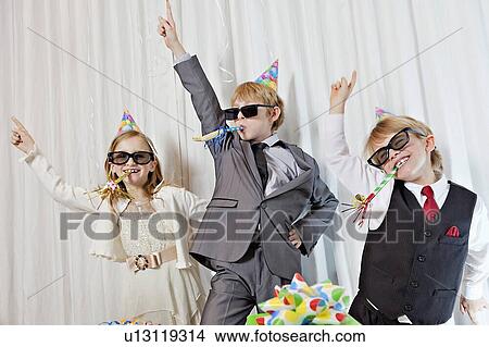Picture - Brothers and sister wearing sunglasses and party puffer in mouth dancing. Fotosearch
