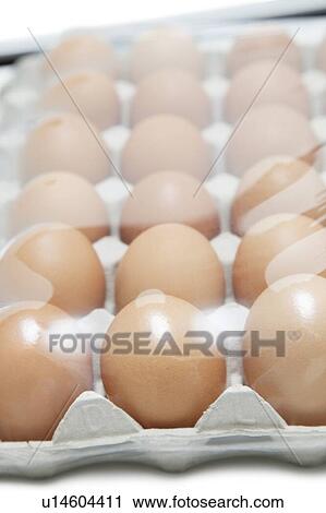 Stock Image - Brown eggs arranged in carton with plastic covering it. Fotosearch