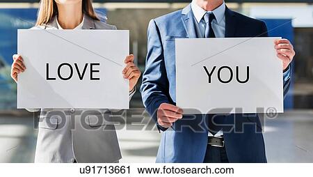 Business couple holding white placard with I love you sign View Large Photo Image Stock Image - Business couple holding white placard with I love you sign. Fotosearch