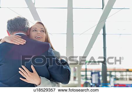 Stock Photo - Business couple reuniting and embracing each other in the airport. Fotosearch