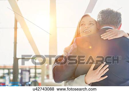 Stock Photo - Business couple reuniting and embracing each other in the airport. Fotosearch