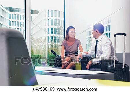 Business couple talking while sitting and waiting in hotel reception area View Large Photo Image Stock Photo - Business couple talking while sitting and waiting in hotel reception area. Fotosearch