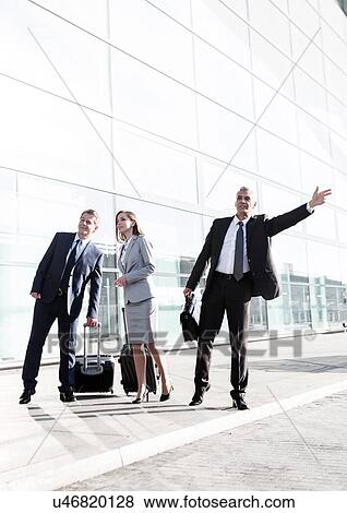 Stock Photo - Business people calling for taxi in the airport. Fotosearch