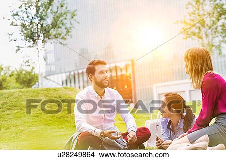 Business people discussing plans while sitting on the grass outdoor View Large Photo Image Picture - Business people discussing plans while sitting on the grass outdoor. Fotosearch