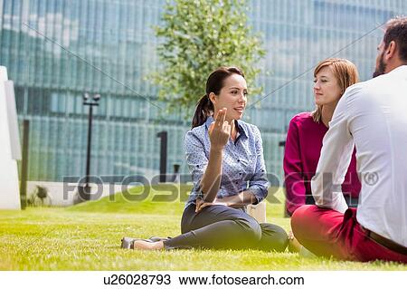 Business people discussing plans while sitting on the grass outdoor View Large Photo Image Stock Image - Business people discussing plans while sitting on the grass outdoor. Fotosearch