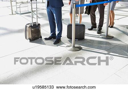 Stock Image - Business people queueing for check in airport. Fotosearch