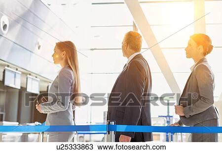 Stock Image - Business people queueing for check in at airport. Fotosearch