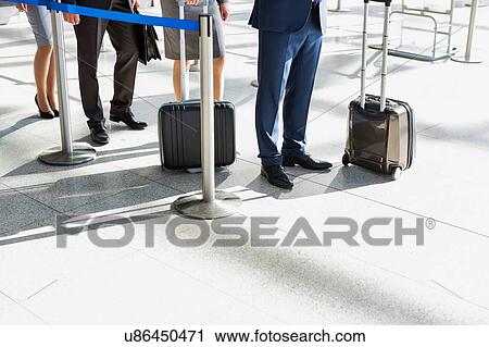 Stock Image - Business people queueing for check in airport. Fotosearch