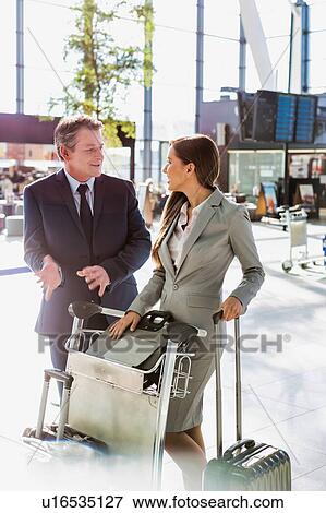 Stock Photo - Business people talking while queueing for check in at airport. Fotosearch
