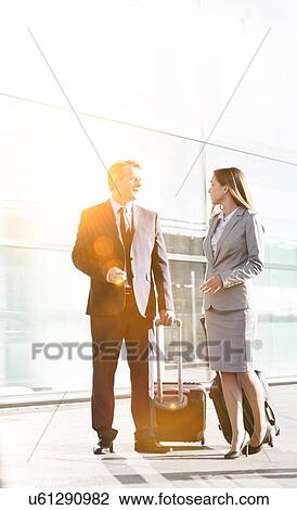 Business people talking while walking with their suitcase in airport View Large Photo Image Stock Image - Business people talking while walking with their suitcase in airport. Fotosearch