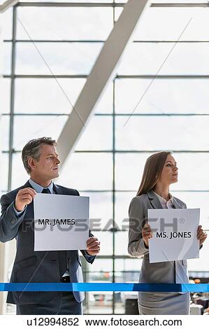 Business people waiting while holding white placard with their boss name in arrival area at airport View Large Photo Image Stock Image - Business people waiting while holding white placard with their boss name in arrival area at airport . Fotosearch