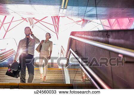 Stock Image - Business people walking downstairs with lens flare in background. Fotosearch
