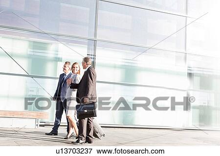 Business people walking while talking in airport View Large Photo Image Stock Photo - Business people walking while talking in airport . Fotosearch