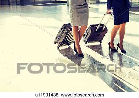 Stock Photo - Business people walking with their suitcase in airport. Fotosearch