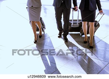 Stock Photo - Business people walking with their suitcase in airport. Fotosearch