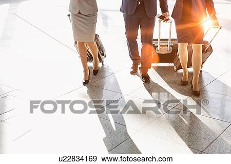 Stock Photo - Business people walking with their suitcase in airport. Fotosearch