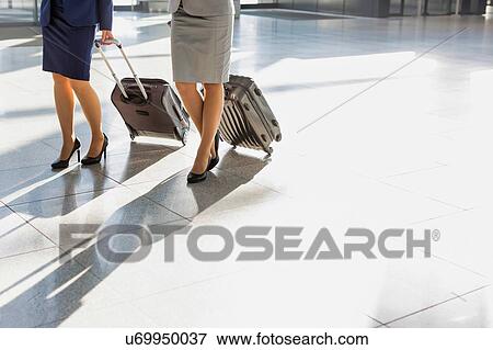 Stock Photo - Business people walking with their suitcase in airport. Fotosearch