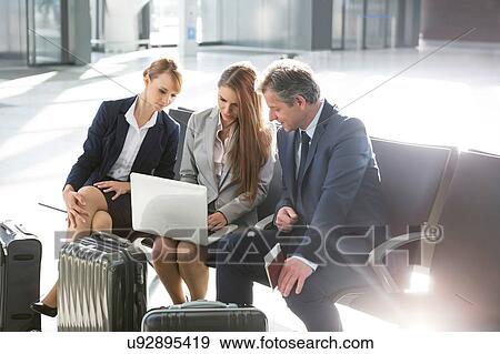 Stock Photo - Business people working while waiting for boarding in the airport. Fotosearch