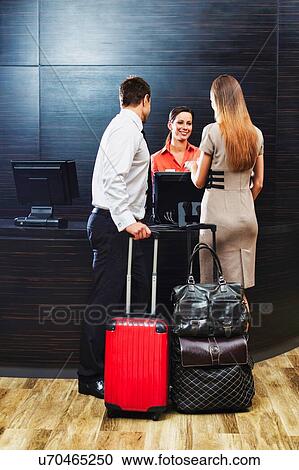 Stock Image - Businessman and businesswoman attending and checking in hotel. Fotosearch