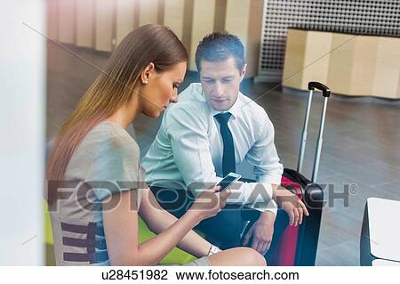 Businessman and businesswoman waiting for their car pick up in hotel lobby View Large Photo Image Stock Image - Businessman and businesswoman waiting for their car pick up in hotel lobby. Fotosearch