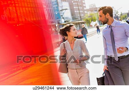 Picture - Businessman and businesswoman walking while discussing plans before meeting. Fotosearch